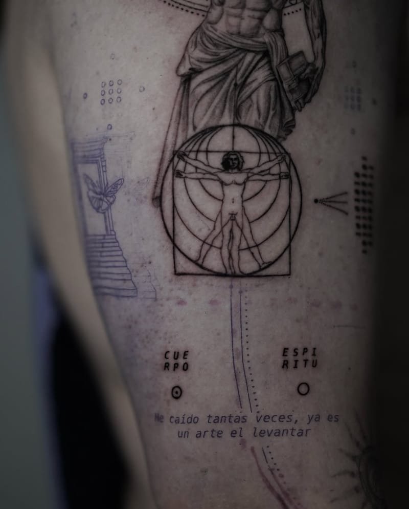 Detalle de la parte baja: el Hombre de Vitruvio y, debajo, las palabras CUERPO y ESPÍRITU partidas en dos líneas, cada una sobre un pequeño círculo; en violeta, todavía sin tatuar, una escalera con una puerta y una mariposa, y la frase He caído tantas veces, ya es un arte el levantar.