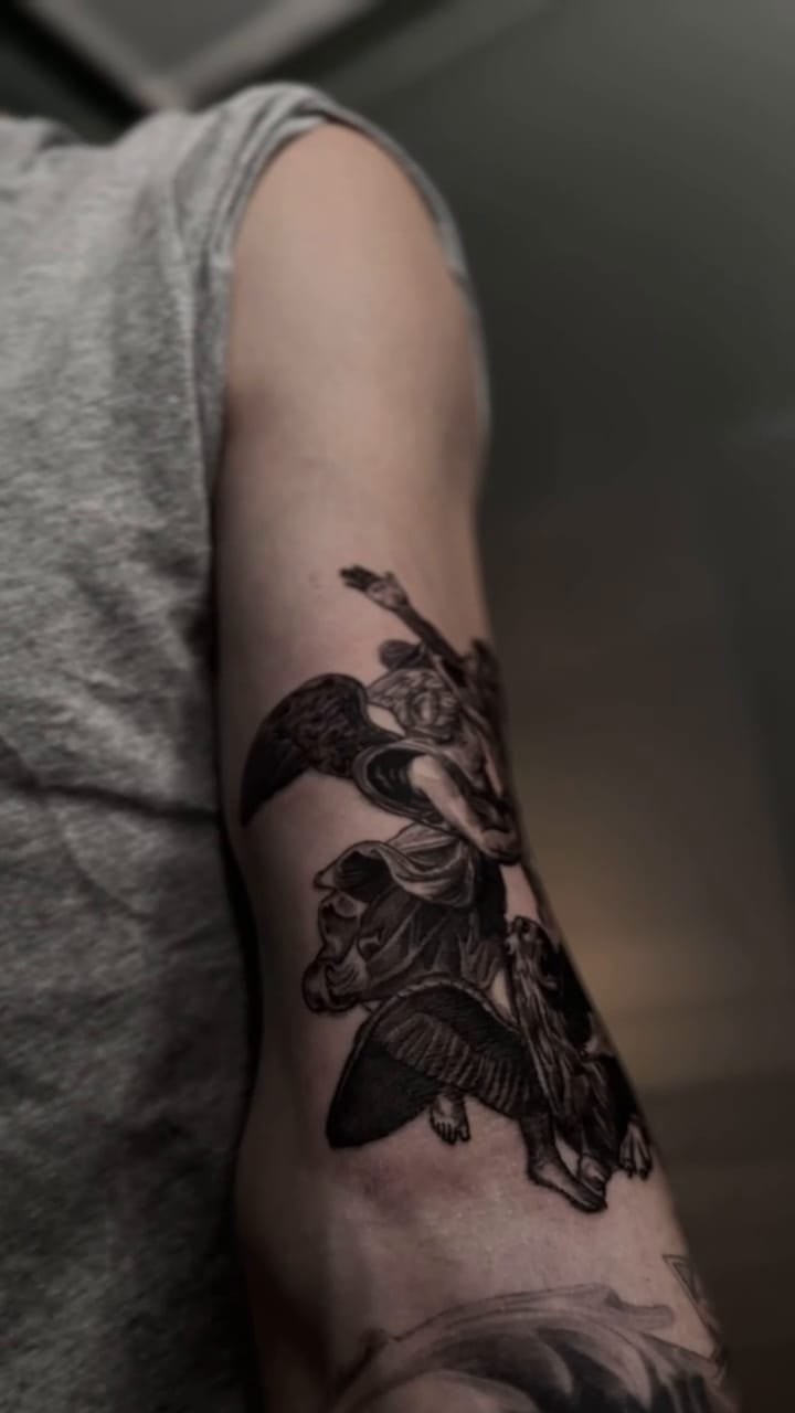 Recorrido en vídeo de un brazo tatuado con un grupo de figuras clásicas entrelazadas y un caballo alado, en negro y gris.
